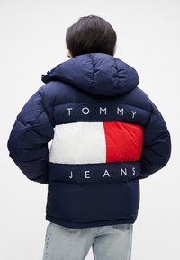 Ναυτική φουτερ με κουκούλα, με λευκή και κόκκινη οριζόντια ρίγα και κείμενο "TOMMY JEANS". Λείος υφασμάτινος σχεδιασμός με επένδυση.