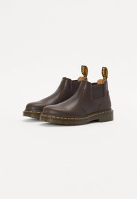 Brune lær ankle boots med elastiske sidepaneler, gul stikning rundt sålen og trækstropper på hælen for nem påtagning.