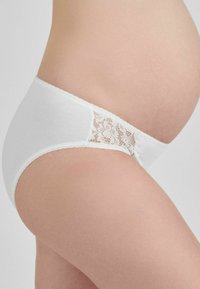 Slip bianco premaman con dettagli in pizzo, realizzato in morbido cotone, con vita elastica e bordi ondulati.