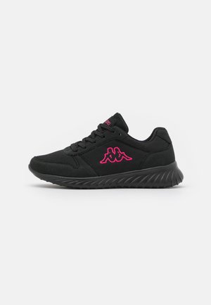 Zapatilla deportiva negra con suela texturizada, logo rosa de dos figuras sentadas en el panel lateral de malla y cordones negros sobre fondo blanco.