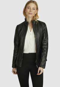 Black leather jacket featuring a zip front, fitted design, and subtle stitching details. Paired with a white button-up shirt.