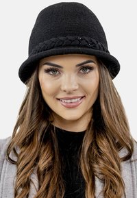 Musta kudottu cloche-hattu, jossa on punottu nauha helmikoristeilla, jämäkkä muotoilu ja sileä pinta. Sopii erilaisiin tilaisuuksiin.