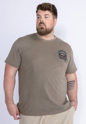 Olijfgroen t-shirt met korte mouwen, een ronde halslijn en een patch op de linkerborst. Gemaakt van katoen met een gladde textuur. Casual pasvorm.