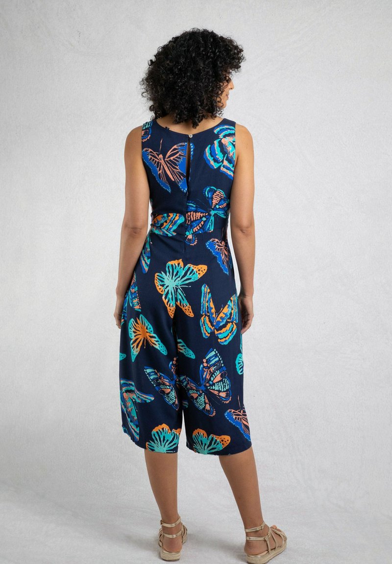 Navy blue jumpsuit with butterfly print in orange and teal, featuring a fitted bodice, wide legs, and a back button closure.