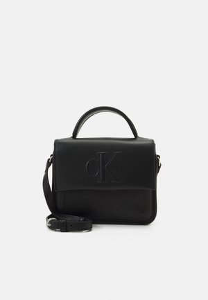 Borsa in pelle nera con un design strutturato, logo "cK" in rilievo, manico superiore e tracolla regolabile. Texture liscia con hardware minimale.