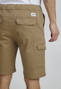 Beiga cargo shorts med dragsko i midjan, två bakfickor och sidfickdetaljer, i en något strukturerad bomullstyg.