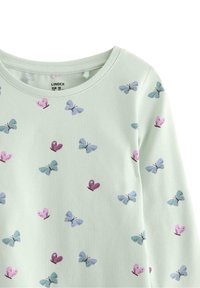 Langærmet lysegrøn bluse med et mønster af blå sommerfugle og pink hjerter. Lavet af blødt stof med en rund halsudskæring.
