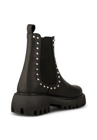 Bottine en cuir noir avec semelle épaisse côtelée et clous argentés bordant le panneau élastique latéral et la languette arrière.