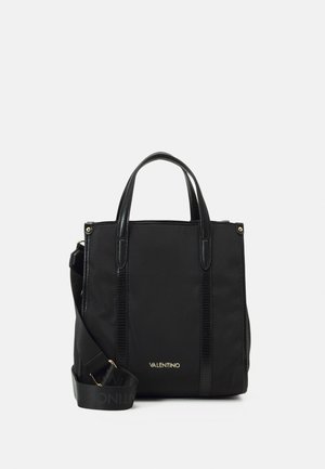 Musta kangaskassi, joka on valmistettu kestävästä kankaasta ja jossa on tyylikkäitä synteettisestä nahasta valmistettuja yksityiskohtia, kaksinkertaiset yläkahvat ja irrotettava olkahihna. Kultaista logoa.