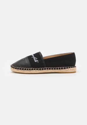 Sort slip-on espadrille med beige syet sål, øvre i stof og læder samt hvidt trykt branding på fronten.