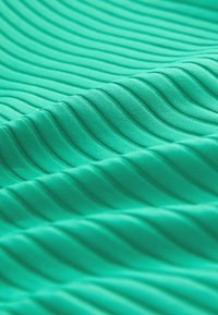 Zelená látka s rovnomerne rozmiestnenou horizontálnou rebrovanou textúrou a jemnými záhybmi vytvárajúcimi vlnité vzory.