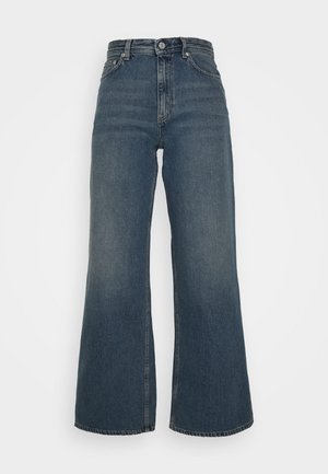 Szerokie, ciemnoniebieskie jeansy z denimu z wysokim stanem, zapięciem na guzik i suwak z przodu oraz pięciokieszeniowym designem na białym tle.