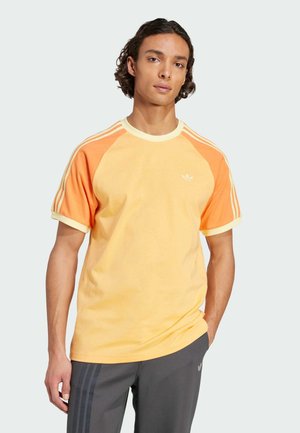 Korte mouw t-shirt in oranje en geel, met een ronde halslijn, witte strepen op de schouders en een klein logo op de borst.