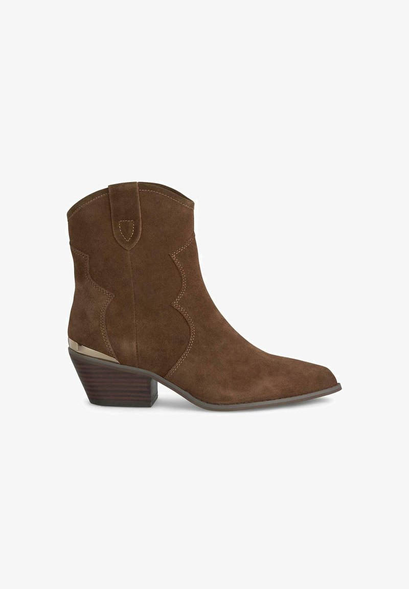 Stivale alla caviglia in suede marrone con punta affusolata, cuciture decorative e tacco a rocchetto. Presenta un accento metallico sul tacco.
