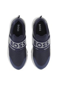 Tengerészkék hálós sportcipők széles szürke pánttal, amelyen "BOSS" felirat található, párnázott szegéllyel és texturált gumi talppal a jobb tapadás érdekében.