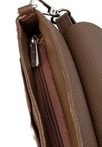 Pruun nahk käekott, mille sisemus näitab tumedamat pruunist kangast lukuga taskut, hõbedase riistvaraga ja tekstuuriga viimistlusega.