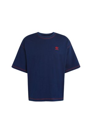 Navy modrá oversized tričko vyrobené z bavlny, se červeným prošitím a malým červeným logem na hrudi. Krátké rukávy a kulatý výstřih.