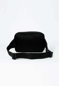 Musta suorakulmainen vyölaukku, jossa on verkkopintainen etuosa ja säädettävä hihna, makaa litteänä valkoisella taustalla.
