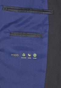Segment kurtki H-ECO w granatowym materiale z czarnymi akcentami, z dwoma poziomymi kieszeniami na zamek błyskawiczny oraz ekologicznymi metkami.