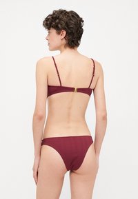 Bordeaux stripete bikini-set med bandeau-top med justerbare stropper og en gullfarget spenne bak, matchende lavt skåret bunn.