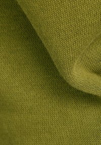Primo piano di un tessuto lavorato a maglia verde oliva che mostra una texture dettagliata e punti fini con pieghe morbide.
