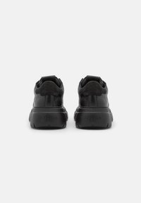 Czarne sneakersy z materiału skórzanego i zamszowego, zaokr�ąglony czubek, wyściółka kołnierza, wyraźny obcas oraz subtelne oznaczenie na pięcie.