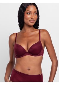 Bordeaux padded beha met verstelbare bandjes, een gladde textuur en een design met een diepe halslijn. Voorzien van naadloze randen en subtiele branding.
