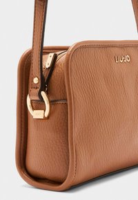 Bruine leren handtas met een gestructureerde afwerking, gouden hardware accenten en een ritsluiting. Bevat een afneembare schouderriem.