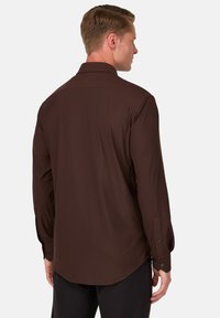 Ruda ilgomis rankovėmis palaidinė su lygia tekstūra, mygtukų rankogaliais ir klasikiniu apykakle. Nugaros pusėje yra išlenktas kraštas.