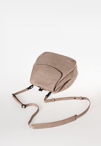 Zaino in pelle beige con forma arrotondata, tasca frontale con chiusura a bottone, tracolla regolabile e superficie liscia. Design minimalista.