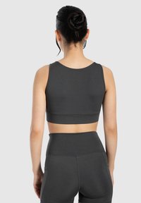 Donkergrijze sportbh van textuurstof, met een ronde halslijn en een brede, geribbelde band aan de onderrand, gecombineerd met bijpassende high-waisted shorts.