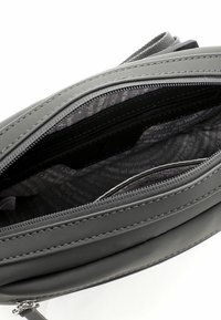 Borsa a spalla grigia con un esterno liscio, multiple tasche con zip e un rivestimento interno a motivo nero. Presenta cuciture e accessori a contrasto.