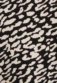 Tissu noir avec un motif abstrait de formes irrégulières beige. La texture semble lisse et douce, adaptée pour les vêtements ou la tapisserie.