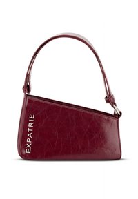 Falošná kožená kabelka v burgundskej farbe s trojuholníkovým tvarom, nastaviteľným remienkom a strieborným kovaním; obsahuje nápis "EXPATRIE" v bielej farbe.