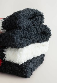 Tre stablede håndklæder: to mørkeblå, et fluffy hvidt. Blød tekstur med en tyk luv. Rene kanter og ingen synlige mønstre eller hardware.