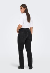 Melnas augsta vidukļa džinsa bikses ar piegulošu siluetu, kuras ir aprīkotas ar klasisku piecu kabatu dizainu. Kombinētas ar baltu īsroku topu.
