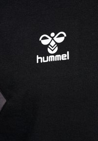 T-shirt nera con un design aderente, caratterizzata da un logo "hummel" bianco e un'icona di ape stilizzata, realizzata in cotone testurizzato.