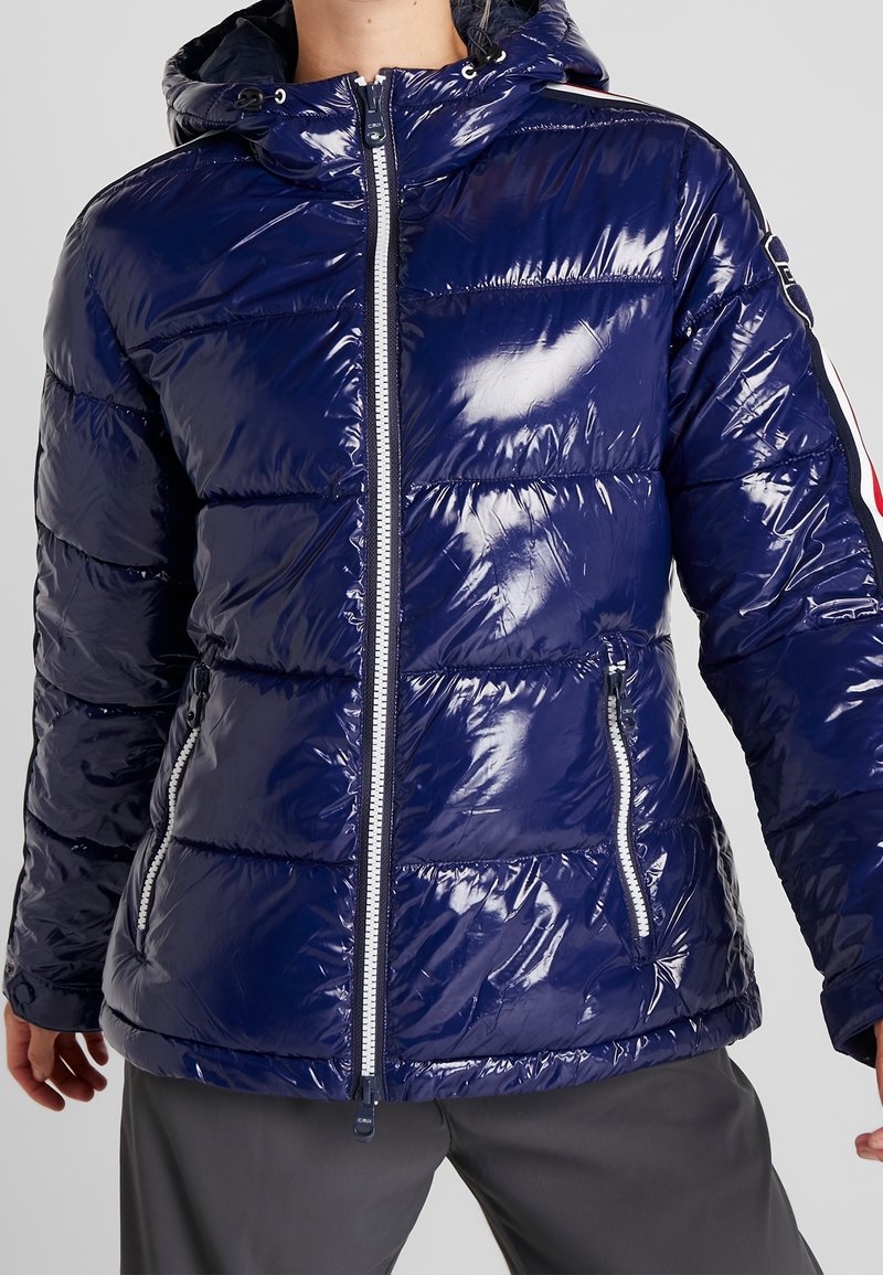 Giacca puffer blu navy con finitura lucida, caratterizzata da una chiusura frontale con zip, cappuccio e strisce laterali a contrasto. Design trapuntato texture.