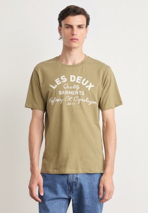 Olive green cotton t-shirt with round neckline, short sleeves, and white text: "LES DEUX Quality Garments Refinery St. Copenhagen 2011."