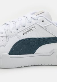 Valge nahast tennisets, millel on teagi suede aktsendid, tekstuuriline detailitus, lame pael ja silmatorkav Puma logo paelade lähedal.