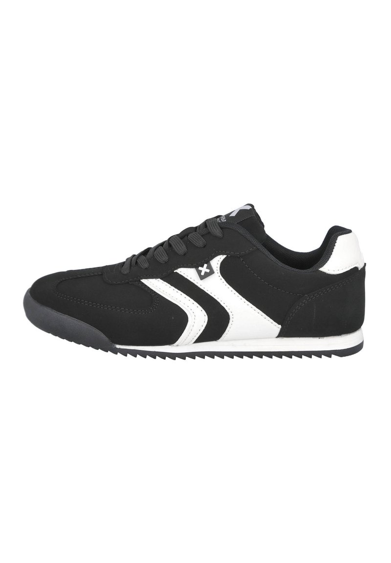 Zapatilla deportiva negra con acentos blancos, con parte superior sintética, diseño con cordones y suela de goma texturizada con patrón de zigzag.
