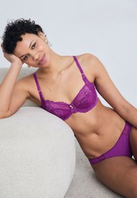 Μωβ δαντελένιο σουτιέν και αντίστοιχες παντόφλες με λεία ύφανση. Το σουτιέν διαθέτει ρυθμιζόμενους ιμάντες και μια διακοσμητική γοητεία στο κέντρο.