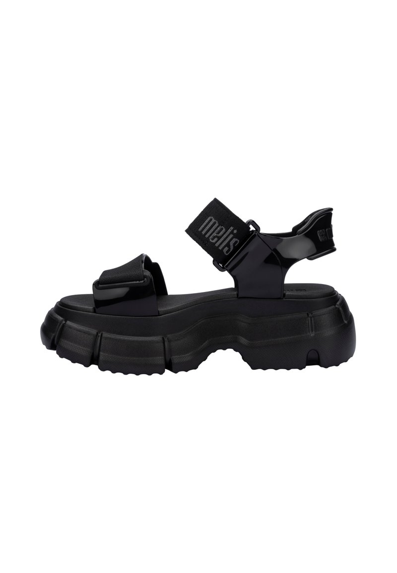 Czarne, masywne sandały z teksturowaną podeszwą, z regulowanymi paskami i błyszczącym wykończeniem. Górna część zawiera oznaczone logo pasek dla dodatkowego detalu.