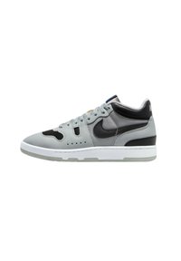 Gray sneaker with a mixed material design, featuring black accents, a perforated toe box, and a white rubber sole. Flat laces, padded collar.