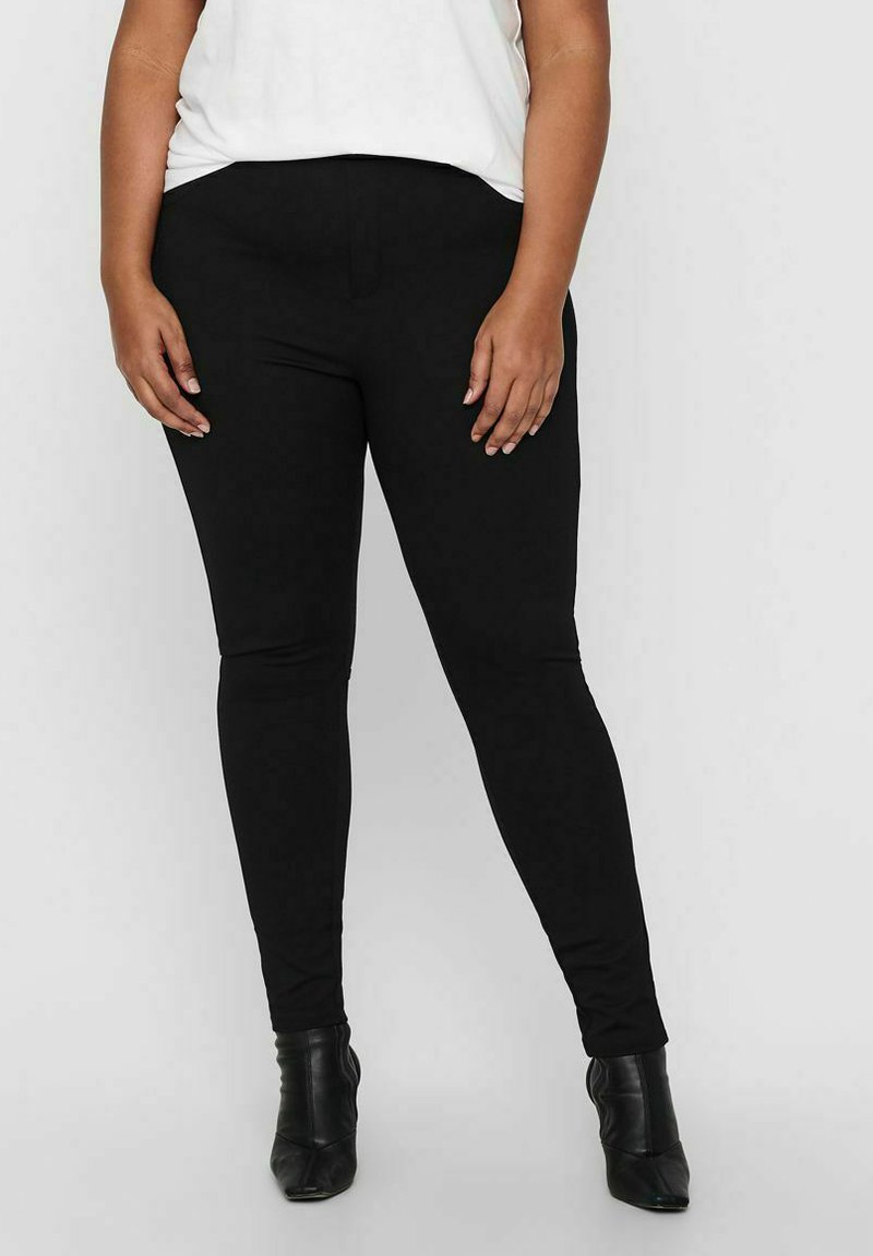 Hochtaillierte schwarze Leggings aus dehnbarem Material, mit einer glatten Textur und figurbetontem Design. Kombiniert mit Knöchelstiefeln.
