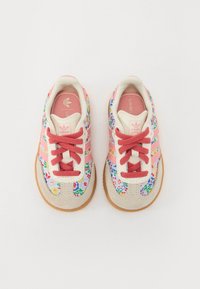 Multi-colored sneakers featuring floral fabric, pink suede accents, and beige leather. Rubber outsole and red laces provide contrast.