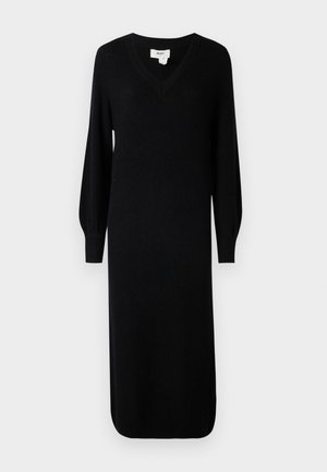 Abito nero a maglia a coste con scollatura a V e lunghe maniche a sbuffo, caratterizzato da un taglio a metà lunghezza e aperture laterali per facilitare i movimenti.