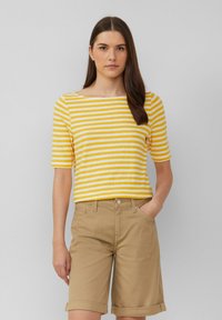 Chemise à manches courtes rayée jaune et blanche avec un col bateau, assortie à un short en kaki clair à ourlet roulé. Design simple, tissu décontracté.