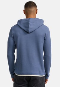 Kapuzensweatshirt in Hellblau, aus strukturiertem Rippstoff, mit langen Ärmeln und abgerundetem Saum, sowie einer kontrastierenden Innenlage.