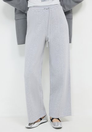Pantalon de survêtement gris clair avec une coupe détendue, doté d'une taille à cordon, de coutures latérales et d'une texture douce. Assorti à des ballerines argentées.